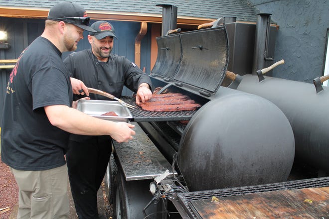Pit cooks Kyle Stewart, left, and Jarrett Celotto pull racks of ribs off the smoker the morning of Friday, April 26, 2019 at Joe Bosco Authentic Smokehouse BBQ. The restaurant opened on April 19 for its second summer season and may soon remain open year-round. [BILL CAMERON/POCONO RECORD]