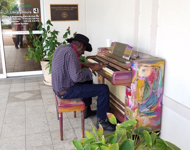 James Camp, 78, plays a communal piano stationed outside the entrance to the Winter Haven Public Library. Camp said he likes to play saloon-style tunes. [GARY WHITE/THE LEDGER]
