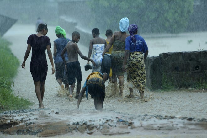 People leave their flooded homes, in Natite neighbourhood, in Pemba, on the northeastern coast of Mozambique on Sunday. Serious flooding began on Sunday in parts of northern Mozambique that were hit by Cyclone Kenneth three days ago, with waters waist-high in areas, after the government urged many people to immediately seek higher ground. [TSVANGIRAYI/MUKWAZHI/THE ASSOCIATED PRESS]