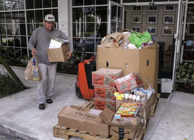 Roberto Sierra, of the Palm Beach County Food Bank, picks up donations Friday at the Palm Beach Daily News for the Empty Your Pantry Food Drive. [Damon Higgins/palmbeachdailynews.com]
