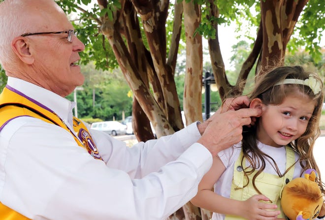 Jim Dame, owner of Gulf Coast Hearing Centers and member of the Panama City Lions Club, installs a special hearing device in the ear of young Skye-Nohea Mizner. The hearing aid is paired with a microphone/transmitter that enables the user to hear directly from the speaker, overcoming effects of central auditory processing disorder. [MICHAEL SNYDER/DAILY NEWS]