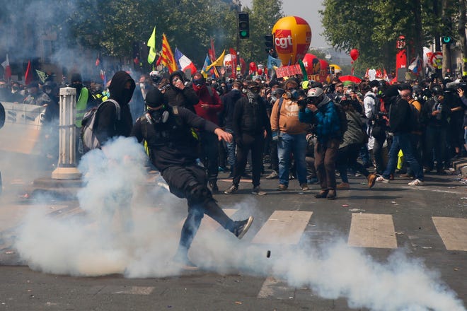 An activist kicks away a tear gas canister during a May Day demonstration in Paris, Wednesday, May 1, 2019. Brief scuffles between police and protesters have broken out in Paris as thousands of people gather for May Day rallies under tight security measures. Police used tear gas to control the crowd gathering near Paris' Montparnasse train station. (AP Photo/Francois Mori)
