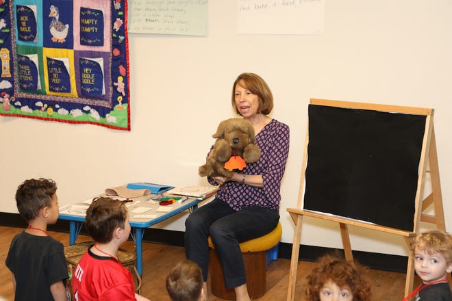 Cathy Chesher, the Adrian District Library youth services librarian, introduces "Charlie" the dog and reads during storytime April 23 at the library.
