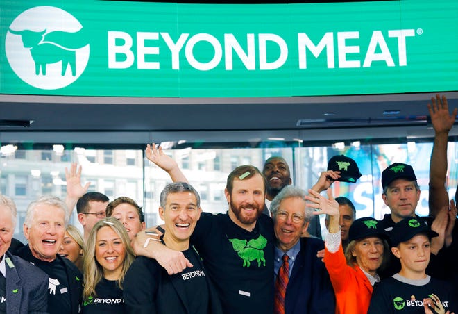 Ethan Brown, center, CEO of Beyond Meat, attends the Opening Bell ceremony with guests to celebrate the company's IPO at Nasdaq, Thursday, May 2, 2019 in New York. California-based Beyond Meat makes burgers and sausages out of pea protein and other ingredients. (AP Photo/Mark Lennihan)