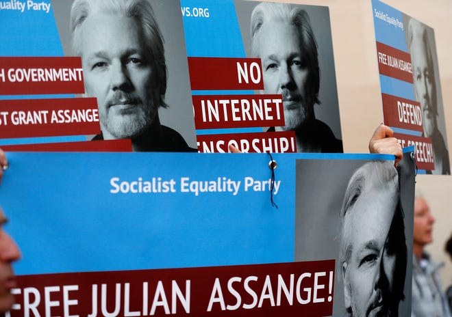 Protestors brandish posters depicting Julian Assange as they demonstrate at the entrance of Westminster Magistrates Court in London, Thursday, May 2, 2019, where WikiLeaks founder Assange is expected to appear by video link from prison. Assange is facing a court hearing over a U.S. request to extradite him for alleged computer hacking.(AP Photo/Frank Augstein)