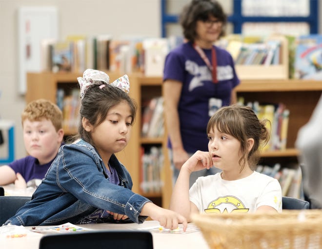 During a bingo game in Spanish, Valeria Gonzalez helps another student play. Valeria said the game was easy for her, but that wasn't the case for her non-Spanish-speaking classmate. [Pittsburg Morning Sun]