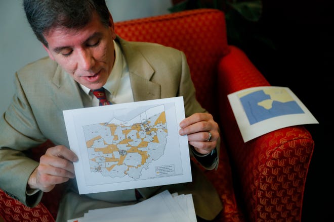 David Niven, a professor of political science at the University of Cincinnati holds a map displaying the wide disparity of Ohio congressional district office locations, with orange locations representing areas whose office are found outside it's own district's bounds, in Cincinnati. A federal court ruled Friday that Ohio's congressional map is unconstitutional and ordered a new one be drawn for the 2020 elections. [John Minchillo/The Associated Press]