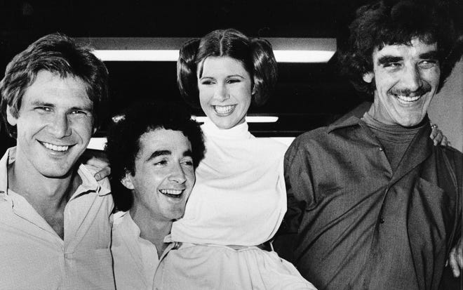 RETRANSMISSION TO CORRECT DAY AND DATE OF DEATH - FILE - In this Oct. 5, 1978 file photo, actors featured in the "Star Wars" movie, from left, Harrison Ford who played Han Solo, Anthony Daniels who played the robot C3P0, Carrie Fisher who played the princess, and Peter Mayhew who played the Wookie, Chewbacca, are shown during a break from the filming of a television special presentation in Los Angeles. Mayhew, who played the rugged, beloved and furry Wookiee Chewbacca in the þÄúStar WarsþÄù films, has died. Mayhew died at his home in north Texas on Tuesday, April 30, 2019 according to a family statement. He was 74. No cause was given. (AP Photo, File)