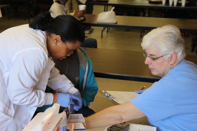Sonia Joyner, RN, left, and Donna Potter, RN, right, work at Mary’s Kitchen during a health screening. [PHOTO COURTESY OF UNC LENOIR HEALTH CARE]