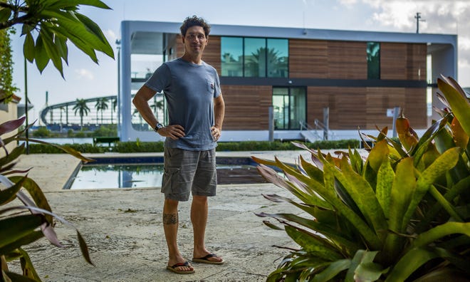 Nicolas Derouin stands in front of the Arkup houseboat, a green-energy luxury floating home that can adapt to sea-level rise. [Miami Herald via TNS / Matias J. Ocner]