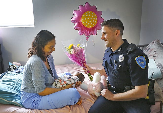 Armed with flowers and a plush bear, Weymouth police officer Paul Torino visits Filomena Salas and her newborn daughter, Olivia, on Monday, May 6, 2019. Torino helped Salas and her husband, Joe Lewandowski, deliver Olivia at their home Saturday. (Greg Derr/The Patriot Ledger)