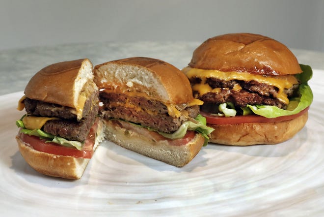 An Original Impossible Burger, left, and a Cali Burger, from Umami Burger, are shown. A new era of meat alternatives is here, with Beyond Meat becoming the first vegan meat company to go public and Impossible Burger popping up on menus around the country. [AP Photo/Richard Drew]