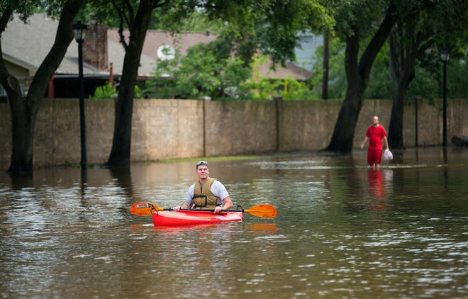Kurt Rowland surveys the scene at the intersection of Austin Parkway and Sweetwater Boulevard in the Colony Bend neighborhood of Sugar Land on Wednesday. Rowland bought the kayak shortly before Hurricane Harvey and was glad to have it, he said. [Mark Mulligan/Houston Chronicle]