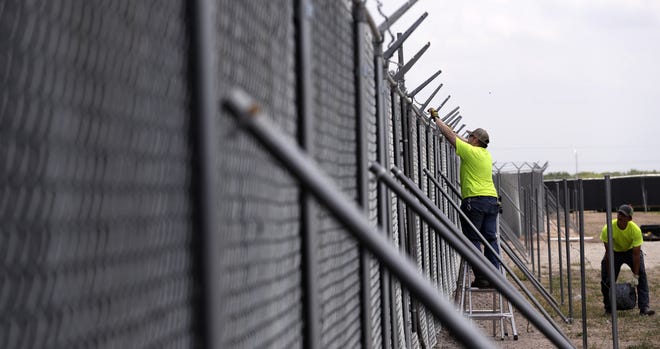 Barbed wire is added to a fence that houses a new U.S. Customs and Border Protection temporary facility near the Donna International Bridge Thursday in Donna, Texas. [AP Photo/Eric Gay]