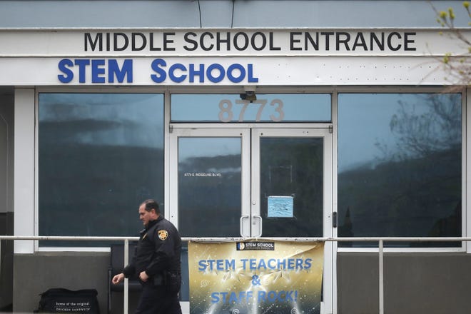 A Douglas County, Colo., Sheriffs Department deputy walks past the doors to the STEM Highlands Ranch school early Wednesday, in Highlands Ranch, Colo. Two high school students used at least two handguns in a fatal Tuesday shooting at the charter school authorities said Wednesday. [David Zalubowski/AP Photo]