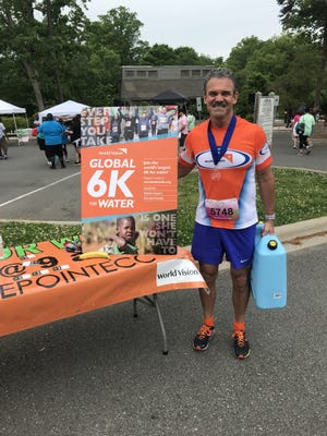 Ray Hardee, lead pastor of The Pointe Church, poses with an informational booth he created after last year's Girls on the Run 5k. Hardee has been participating in local races to promote the World Vision Global 6k for Water, to be held Saturday, May 11. [SUBMITTED PHOTO]