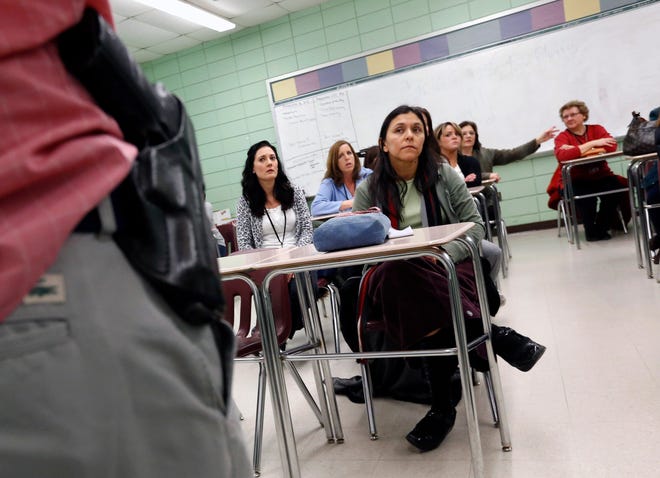 FILE - In this March 15, 2013, file photo, teacher Astrid Barrios, center, listens as Milford police detective Carlos Sousa, left, debriefs participants after a lockdown exercise at Milford High School in Milford, Mass. The actions of students who died tackling gunmen at two separate U.S. campuses a week apart have been hailed as heroic. At a growing number of schools around the country, they also reflect guidance to students who are told, at least in some situations, to do what they can to disrupt shootings. (AP Photo/Michael Dwyer, File)