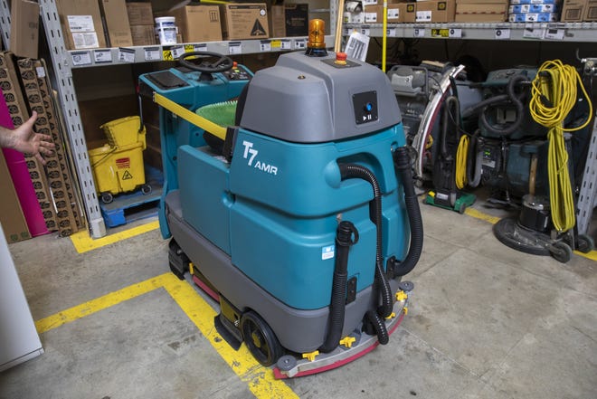 The new automated floor scrubbers at Walmart are kind of like a giant Roomba, replacing the manual push versions seen to the right. They roam the store autonomously, stopping and steering around customers. [Bettina Hansen/ The Seattle Times via TNS]