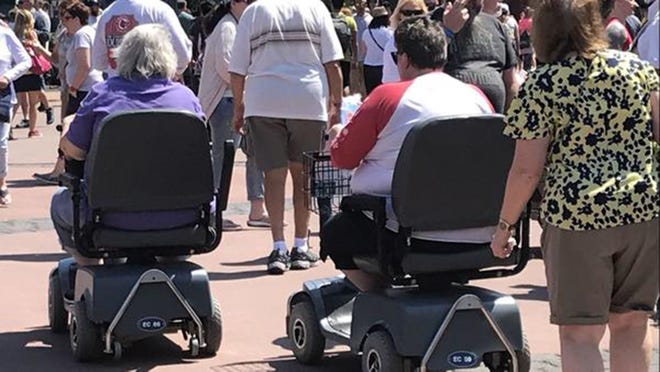 Two scooter users move through Epcot during the Flower and Garden Festival on March 21. [Gabrielle Russon/Orlando Sentinel/TNS]