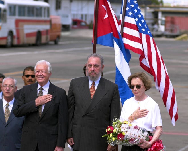 Former U.S. President Jimmy Carter, center left, places his hand over his heart during the playing of the United States' national anthem, standing with Cuban President Fidel Castro, and former First Lady Rosalynn Carter, after the Carters' arrival to Havana, Cuba, on May 12, 2002. Carter was the first U.S. president, in or out of office, to visit Cuba since the 1959 revolution that put Castro in power. [Cristobal Herrera/The Associated Press]