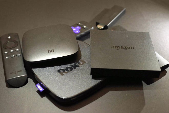 This Nov. 16, 2016, file photo shows Xiaomi's Mi Box, left, the Roku Premiere, center, and the Amazon Fire TV streaming TV devices in New York. An outside search aid such as Roku, Reelgood, Decider and JustWatch can help scan multiple services to see which ones have the titles you want to watch. [ASSOCIATED PRESS]