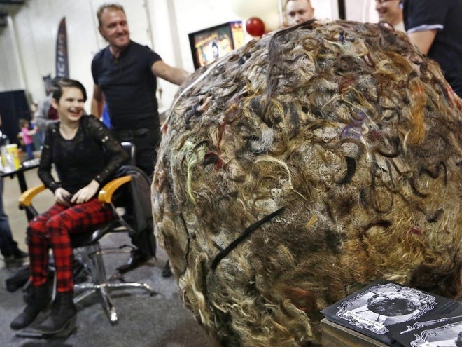 A Cambridge, Ohio, man has created a 125-pound ball of human hair, which he showed at the Ohio Expo Center on Saturday, cutting people's hair to add to his creation. Steve Warden hands a lock of hair cut from Tyra May, of Springfield, to an assistant to adhere to the giant hair ball. [FRED SQUILLANTE/COLUMBUS DISPATCH]