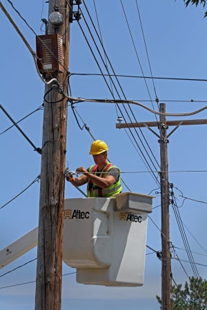 A sub-contractor readies telephone poles to string stainless steel strand cables to carry fiber-optic cable. [TNS file]