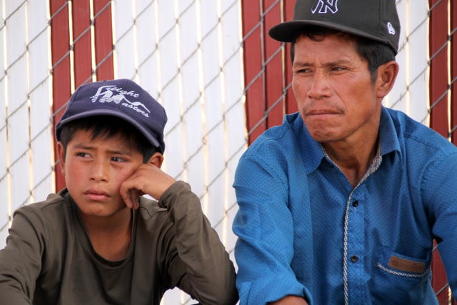 Guatemalan father and son, Felipe Perez Pablo, and Felipe Perez Andres, 12, sit at the Mimbres Food Mart waiting to board a bus for Tennessee on Wednesday..