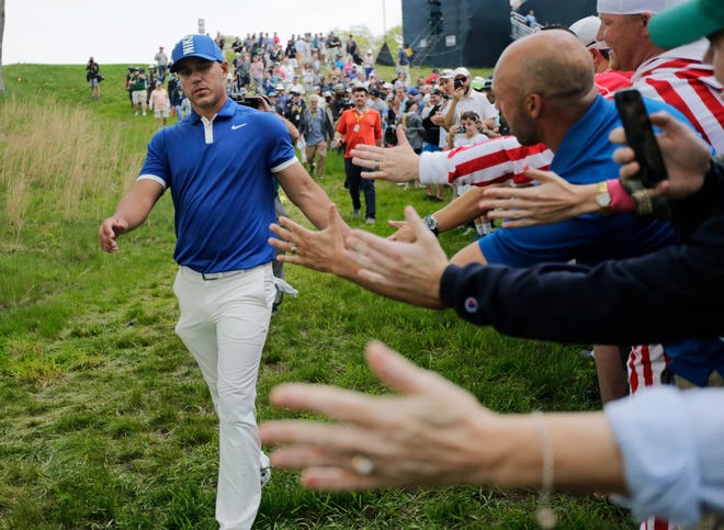 Brooks Koepka greets spectators as he walks down to the 15th tee during the second round of the PGA Championship at Bethpage Black in Farmingdale, N.Y. [Charles Krupa/The Associated Press]