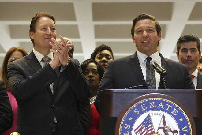In this May 4 photo, Florida Gov. Ron DeSantis, center, is applauded by Senate president Bill Galvano, R-Bradenton, left, at the end of session in Tallahassee. [AP Photo/Steve Cannon/File]