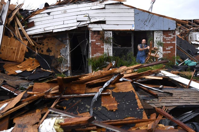 Wesley Mantooth lifts a wooden chair from the window of the father's storm-hit home Saturday in Abilene, where severe storms — and possibly a tornado — damaged several houses. [Ronald W. Erdrich/The Abilene Reporter-News]