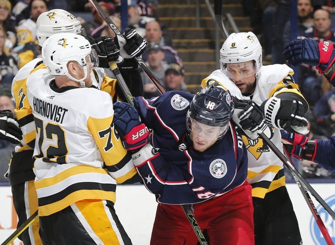 Columbus Blue Jackets center Pierre-Luc Dubois (18) takes a shot in the back of the head from Pittsburgh Penguins defenseman Brian Dumoulin (8) in front of right wing Patric Hornqvist (72) and center Evgeni Malkin (71) during the third period of the NHL game at Nationwide Arena in Columbus on March 9, 2019. The Blue Jackets won 4-1. [Adam Cairns]