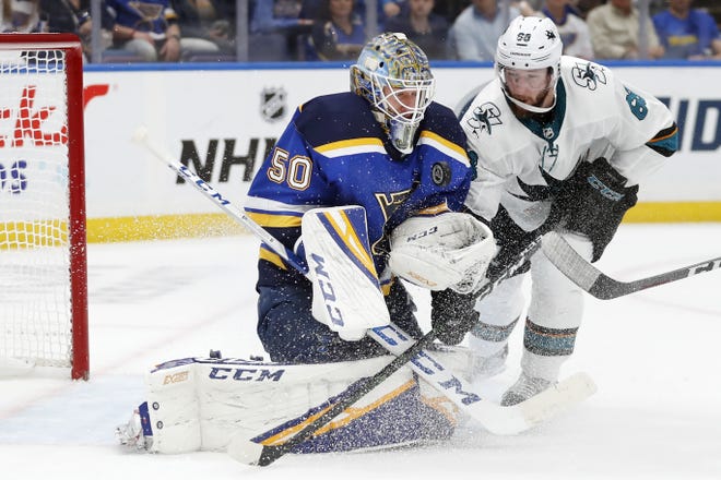 St. Louis Blues goaltender Jordan Binnington (50) protects the puck as San Jose Sharks center Melker Karlsson (68), of Sweden, closes in during the second period in Game 4 of the NHL hockey Stanley Cup Western Conference final series Friday, May 17, 2019, in St. Louis. (AP Photo/Jeff Roberson)