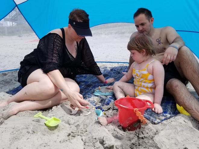 Nadine and Michael Haskin sit with their 5-year-old daughter, Ila, as she plays with seashells at Atlantic Beach during Mile of Hope on May 11. Ila was diagnosed with DIPG, an aggressive brain tumor, 18 months ago. Nadine Haskin said the beach is one of Ila's favorite places to be. [Amanda McReynolds/The Jacksonville Daily News]