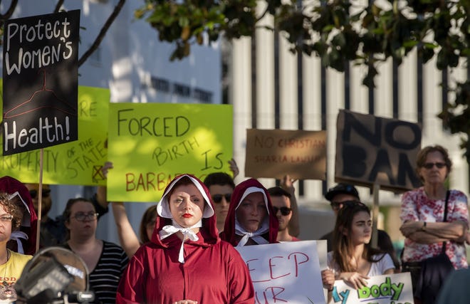 A woman dressed as a handmaid protests against a ban on nearly all abortions outside of the Alabama State House in Montgomery, Ala., on Tuesday. [MICKEY WELSH/THE MONTGOMERY ADVERTISER via AP]
