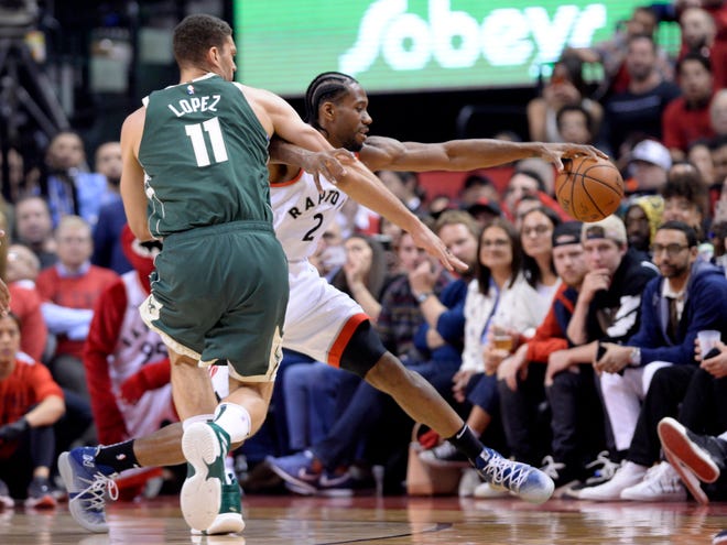 Toronto Raptors forward Kawhi Leonard (2) keeps the ball in bounds in front of Milwaukee Bucks center Brook Lopez (11) during the first half of Game 3 of the NBA playoffs Eastern Conference finals in Toronto on Sunday. [NATHAN DENETTE / THE CANADIAN PRESS VIA AP]