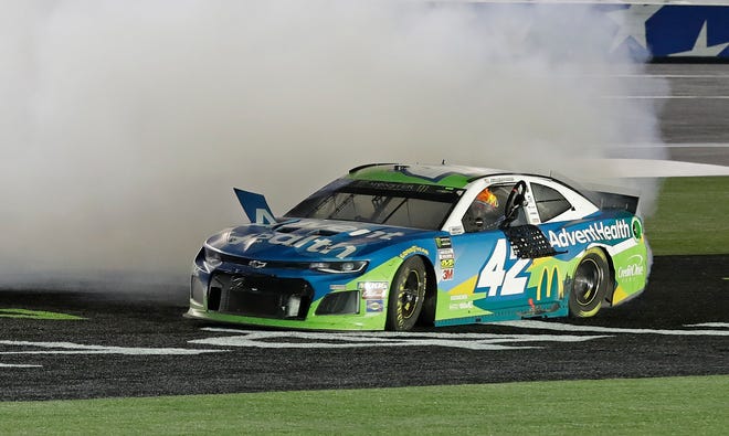 Kyle Larson holds the steering wheel out of his car as he does a burnout Saturday night after winning the Monster Energy NASCAR All-Star Race at Charlotte Motor Speedway in Concord, N.C. [Chuck Burton/The Associated Press]