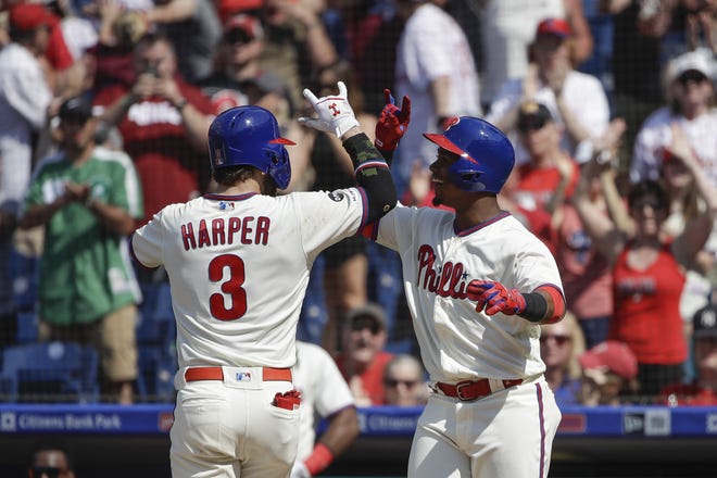 The Phillies' Bryce Harper celebrates with Jean Segura after Harper hit a go-ahead home run in the sixth inning of Sunday's 7-5 win over the Rockies. [MATT ROURKE / ASSOCIATED PRESS]