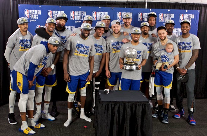 The Golden State Warriors players pose with the Western Conference Championship trophy after Game 4 of the Western Conference finals on Monday. [AP Photo/Craig Mitchelldyer]