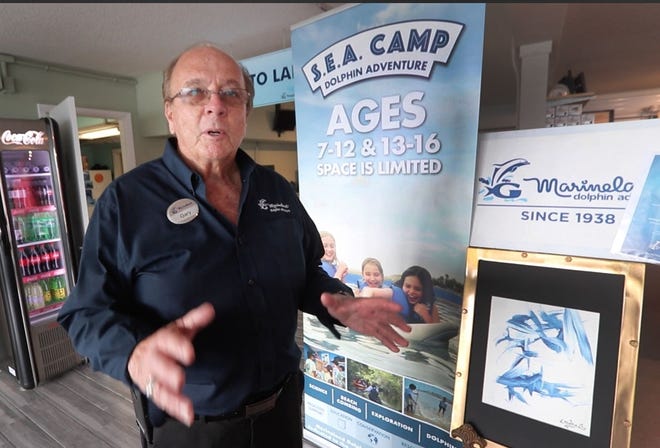 Gary Inks, former vice president and general manager at Marineland Dolphin Adventure, shows off one of the original brass window frames now holding a painting by 'Nellie' the dolphin as part of the attraction's 80th anniversary last year. Inks resigned from the Flagler County Tourist Development Council earlier this month citing the sale of the attraction to Cancun, Mexico-based Dolphin Discovery. [ News-Tribune file]