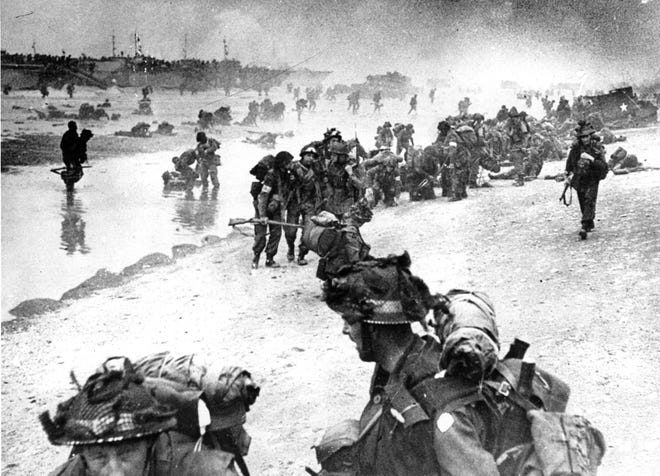 Troops move on the Normandy shore from their landing craft in this June 6, 1944 file photo during the D-Day invasion of German-occupied France during World War II. [AP FILE PHOTO]