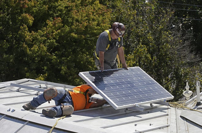 Workers install a solar panel on a rooftop. [AP Photo/Rich Pedroncelli, File]