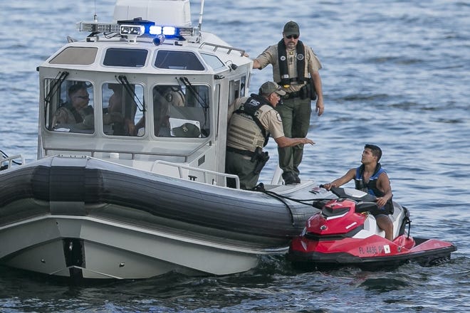 Officers with the Florida Fish & Wildlife Conservation Commission talk to a man on a personal watercraft at the Boca Bash on Lake Boca Raton on Sunday, April 28, 2019 in Boca Raton, Florida. More than 10 people were arrested on BUI charges at the event, and the FWC will be patrolling area waters with 'zero tolerance' for those who boat while intoxicated. [GREG LOVETT/palmbeachpost.com]