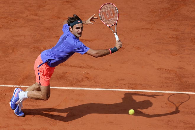 Roger Federer makes a return against Switzerland's Stan Wawrinka during a 2016 quarterfinal match at the French Open in Paris, France. [David Vincent/The Associated Press]