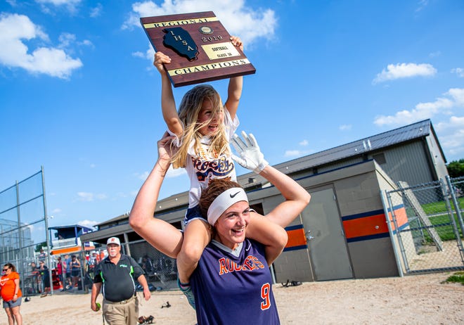 Blakely Howard, 5, hoists the championship plaque on top the shoulders of Rochester High School's Reagan Miles after the Rockets defeated Clinton 4-0 in the Class 3A Rochester Regional championship game Friday. [Justin L. Fowler/The State Journal-Register]