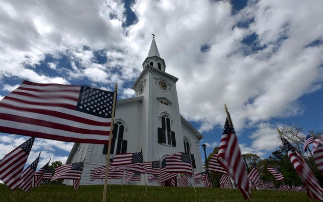 The wind unfurls the flags set out for Memorial Day weekend at the First Congregational Church of Yarmouth. Towns across the Cape will hold observances of the holiday this weekend beginning today. [STEVE HEASLIP/CAPE COD TIMES]