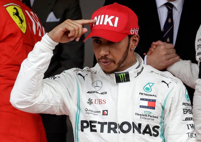 Mercedes driver Lewis Hamilton of Britain, center, points to his hat to tribute Niki Lauda after he won the Monaco Formula One Grand Prix race at the Monaco racetrack in Monaco on Sunday. [Luca Bruno/The Associated Press]