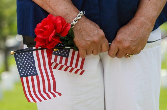 A woman grasps her flags and flowers during Memorial Day services at Camp Butler National Cemetery Monday, May 25, 2015. [Ted Schurter/The State Journal-Register]