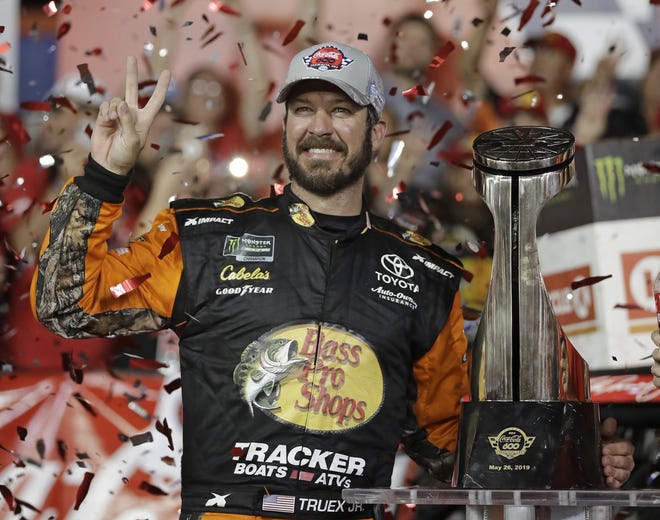 Martin Truex Jr. poses with the trophy in Victory Lane after winning the NASCAR Cup Series race at Charlotte Motor Speedway on Sunday in Concord, N.C. [AP Photo/Chuck Burton]