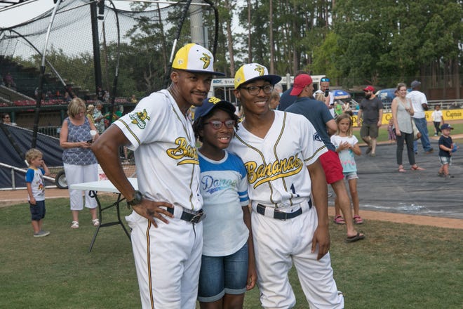 Gabbi Frazier has her photo taken with Savannah Bananas coaches and team members Mace Harrison and Darius Johnson at Monday's Fan Fest at Grayson Stadium.[RANDY THOMPSON/SAVANNAHNOW.COM]